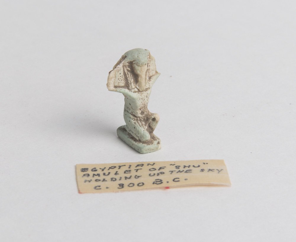 Ancient Egyptian Faience Amulet of god Shu Ca. 525 B.C: Ancient Egyptian Faience Amulet of god Shu Ca. 525-300 B.C. Size 27 x 16 mm. Light blue faience amulet of god Shu modeled with fine details, holding the sun, on rectangular base with suspension loop o