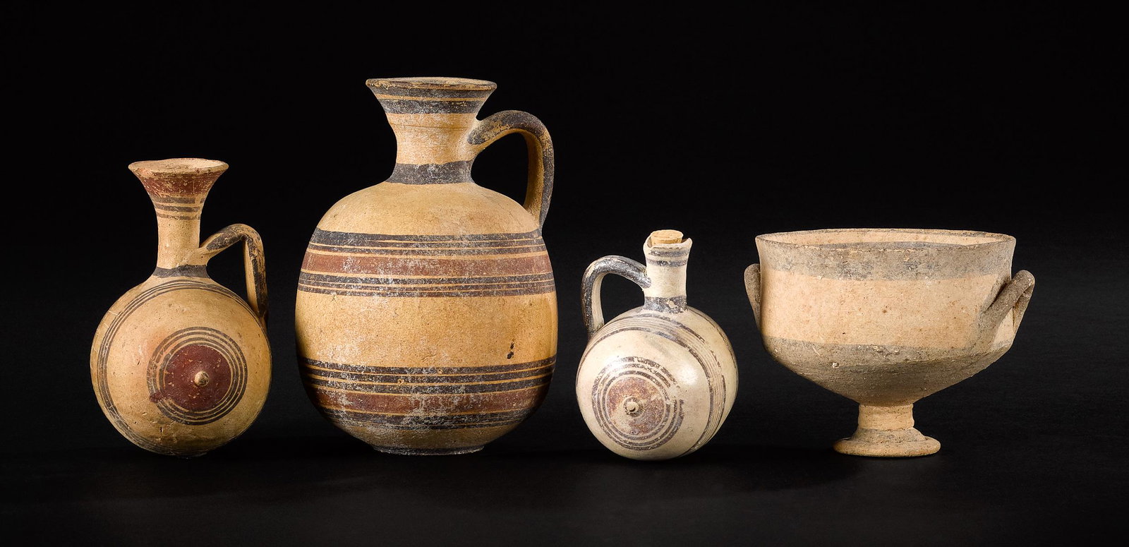 Four pieces of Cypriot pottery: Four pieces of Cypriot pottery, 750-600 B.C., to include a skyphos, two nipple flasks and one oinochoe, all painted with concentric rings in black and red ochre, tallest - 6 1/4'' h. Provenance: First