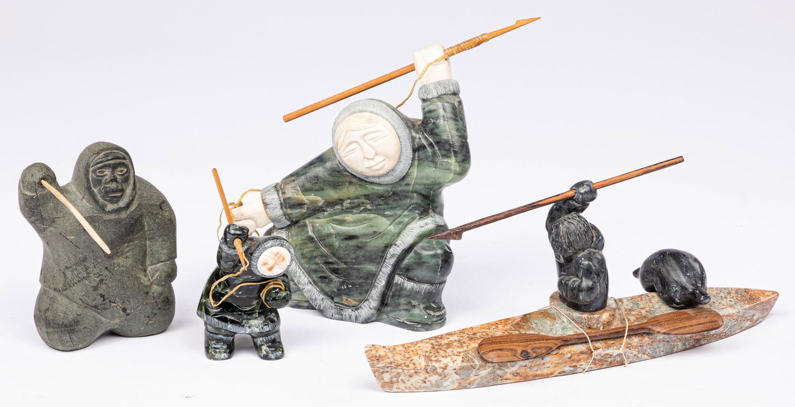 Four Inuit stone and bone carvings of hunters: Four Inuit stone and bone carvings of hunters, to include a figure in a kayak, signed Panniniak 11 3/4'' l.