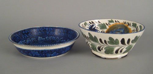 Pearlware bowl, 19th c., with blue, green, and: Pearlware bowl, 19th c., with blue, green, and ochre floral decoration, 10'' dia., together with a Staffordshire blue and white bowl with grapevine border and street scene, 11 1/2'' dia.