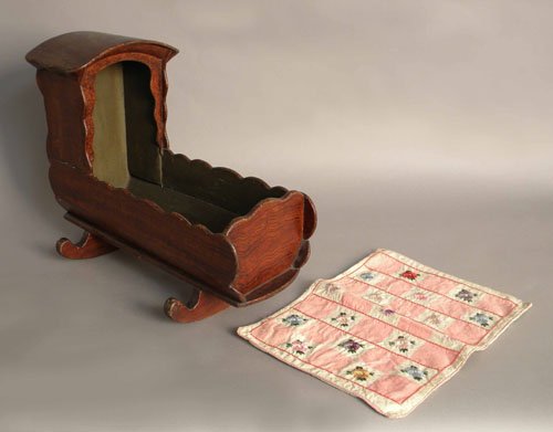 Painted doll cradle, 19th c., 15'' h., 18 1/2'' l.,: Painted doll cradle, 19th c., 15'' h., 18 1/2'' l., together with a doll quilt.