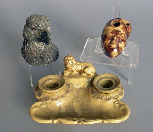 Two figural inkwells, 19th/20th c., one Benningto: Two figural inkwells, 19th/20th c., one Bennington type of a man in a night cap, 2'' h., the other a spelter eagle, 3 1/8'' h., together with a yelloware standish with lion.