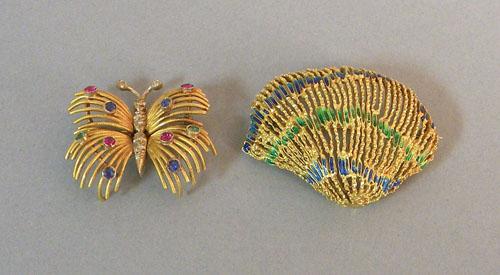 Two 18K yellow gold brooches, the first with fili: Two 18K yellow gold brooches, the first with filigree shell with green and blue enamel, 38 mm x 29 mm, 6.9 dwt., the other with butterfly and four blue sapphires, two emeralds, four rubies on wings, t