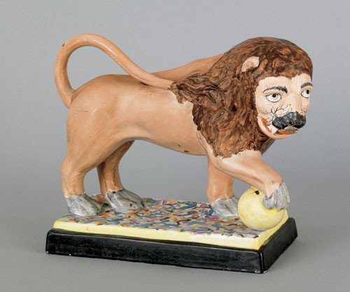 Staffordshire pearlware figure of a lion, early: Staffordshire pearlware figure of a lion, early 19th c., with a paw resting on an orb, 8 3/4'' h., 11'' w.