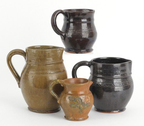 Four Stahl redware pitchers, 19th c., the large: Four Stahl redware pitchers, 19th c., the largest pitcher by Thomas Stahl, dated 1935, inscribed on bottom with squirrel and gun, the others dated 1936, 1947, and 1948, tallest - 7 1/4'' h.