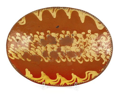 Pennsylvania slip decorated oval redware loaf di: Pennsylvania slip decorated oval redware loaf dish with extensive yellow slip decoration, 10 3/4'' x 14 1/4''.