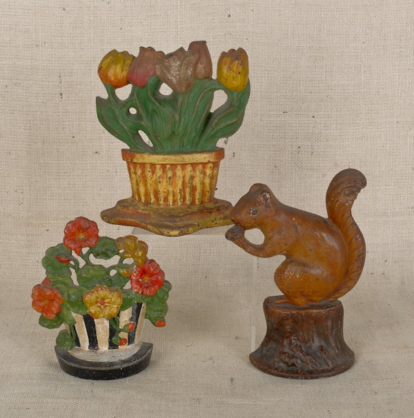 Three painted cast iron doorstops, ca. 1900, to: Three painted cast iron doorstops, ca. 1900, to include a squirrel and two flower baskets, tallest - 9 1/4'' h.
