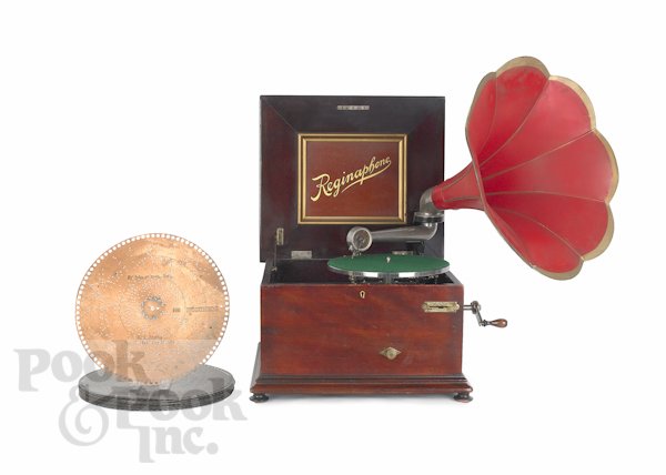 Reginaphone music box, ca. 1900, with a mahogany: Reginaphone music box, ca. 1900, with a mahogany case, a double comb, a painted tin morning glory horn, a record turn table attachment, and twelve 12'' dia. discs, 10 1/2'' h., 17'' w.