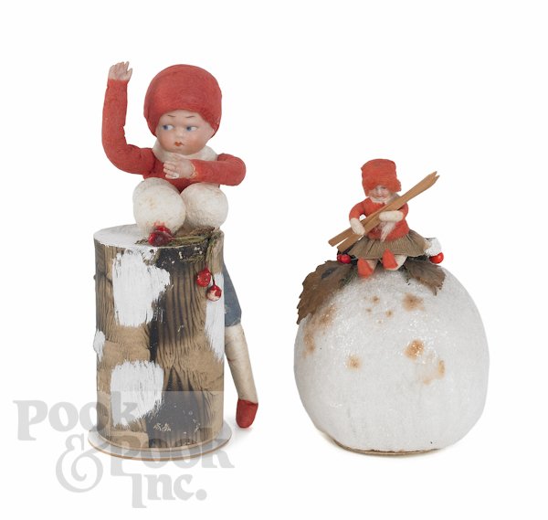 Two German Heubach Christmas candy containers, ca: Two German Heubach Christmas candy containers, ca. 1900, one of a boy at a stump throwing snowballs, 6 1/2'' h., the other of a girl with skis seated on a snowball, 4 1/2'' h.