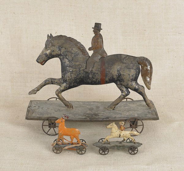 Three painted tin pull toys, to include a large: Three painted tin pull toys, to include a large horse and rider, a stag, and a small horse and rider, largest - 10 1/2'' h., 13'' w.
