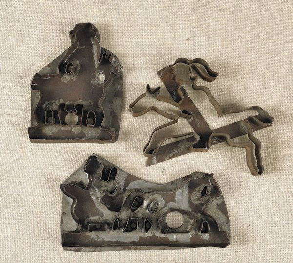 Three tin sheet iron cookie cutters, 19th c., d: Three tin sheet iron cookie cutters, 19th c., depicting a horse drawn sleigh, 5 1/8'' h., 8 3/4'' w., and two figures on horseback.