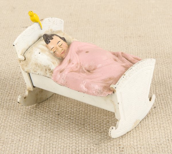 Cast iron baby in a cradle still bank, 3 3/4'' l.: Cast iron baby in a cradle still bank, 3 3/4'' l.