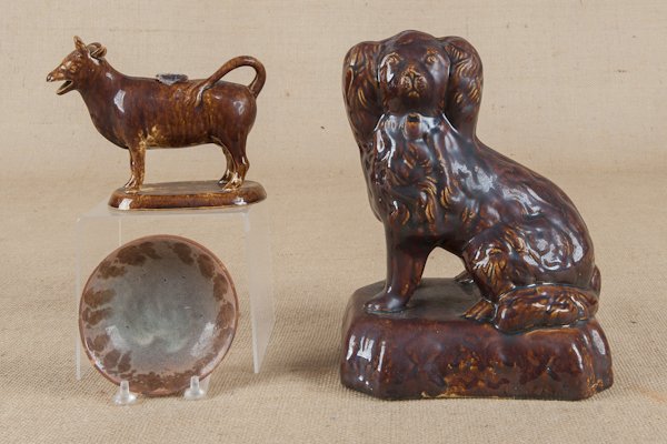 Yelloware spaniel, 19th c., 10'' h., together with: Yelloware spaniel, 19th c., 10'' h., together with a Rockingham glaze cow creamer and a Stahl redware bowl.