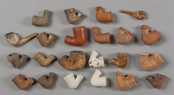 Group of earthenware pipes, together with a Nativ: Group of earthenware pipes, together with a Native American basket.