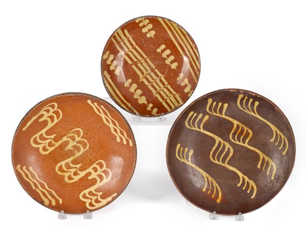 Three Pennsylvania slip decorated redware plates: Three Pennsylvania slip decorated redware plates, 19th c., 11'' dia., 10 3/4'' dia., and 8 7/8'' dia.