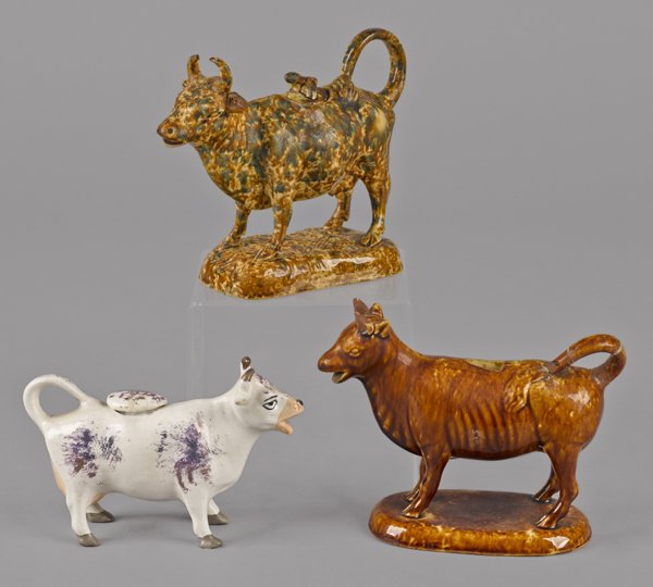 Yelloware flint glaze cow creamer, 19th c., 6'' h.: Yelloware flint glaze cow creamer, 19th c., 6'' h., together with a Bennington type cow creamer, 5 3/4'' h., and a lustre example.
