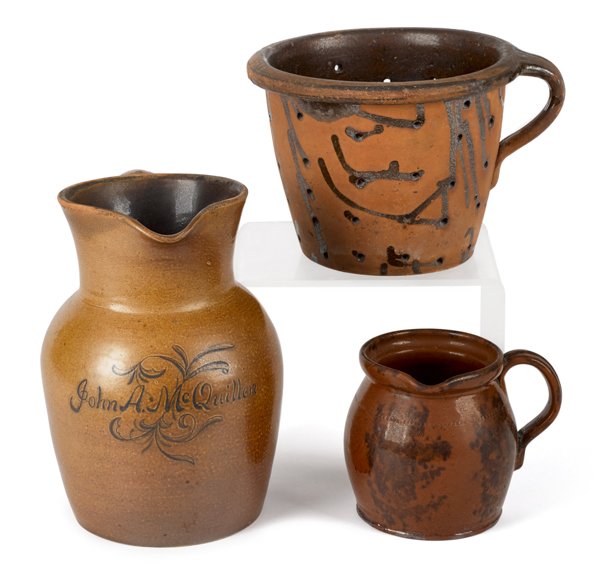 Stoneware pitcher, late 19th c., inscribed John: Stoneware pitcher, late 19th c., inscribed John A. McQuillen, with a cobalt floral sprig, 9 1/2'' h., together with a redware colander and a pitcher.