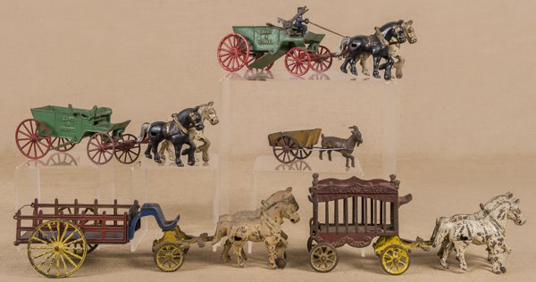 Four cast iron horse drawn wagons, to include Ov: Four cast iron horse drawn wagons, to include Overland Circus and Sand & Gravel, together with a goat drawn wagon, longest - 18''.