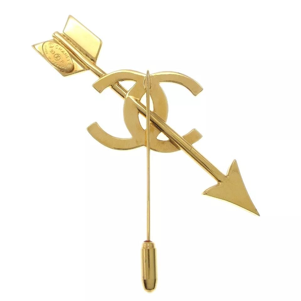 CHANEL BOW AND ARROW MOTIF BROOCH PIN CORSAGE GOLD-TONE: CHANEL BOW AND ARROW MOTIF BROOCH PIN CORSAGE GOLD-TONE CONDITION Exterior: A; GOOD CONDITION!! Scratched Number : 93P Size (Inch) : W 3.1 " x H 3.3 " Size (CM) : W 8.0 x H 8.5 cm Color : Gold Materia