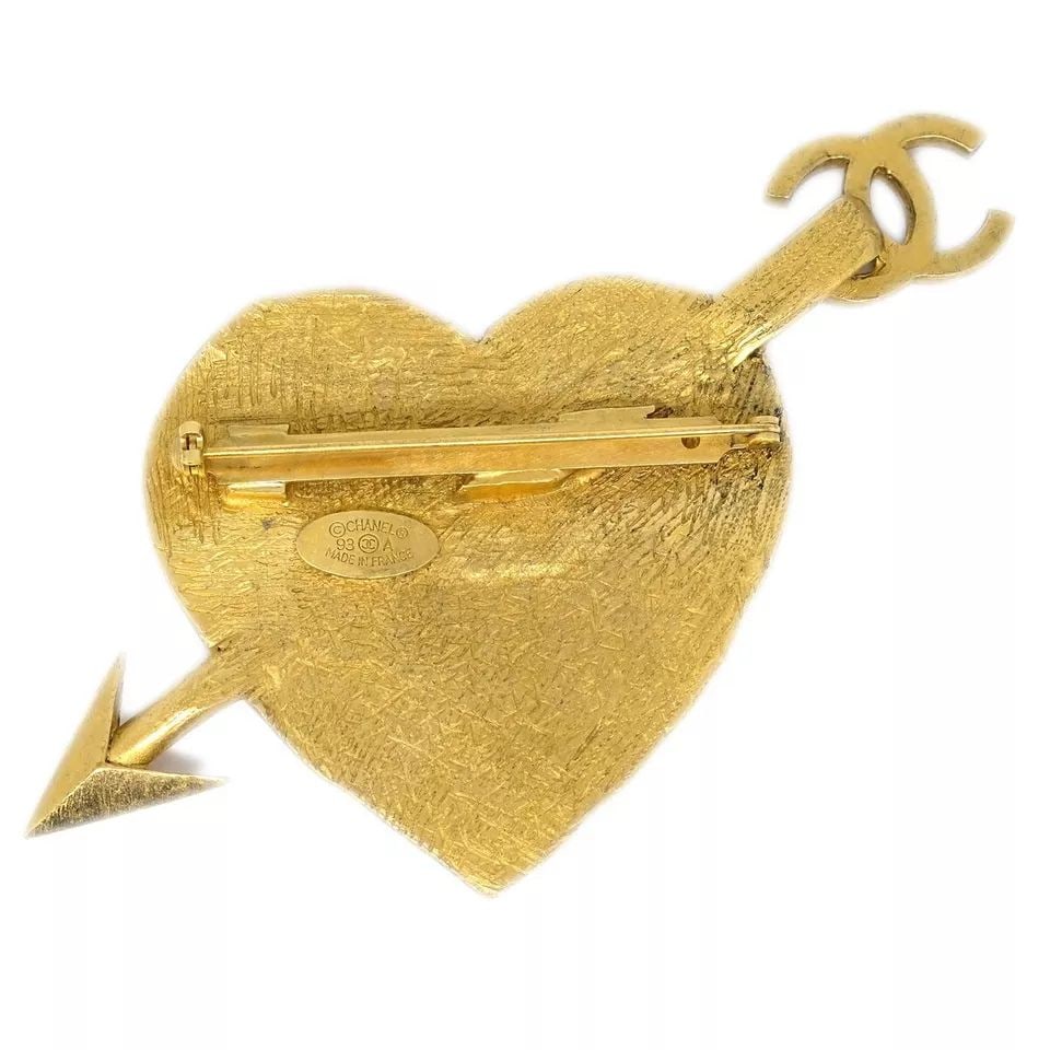 CHANEL GOLD BOW AND ARROW HEART BROOCH PIN 93A: CHANEL GOLD BOW AND ARROW HEART BROOCH PIN 93A CONDITION Exterior: A : GOOD CONDITION!! Number : 93A Size(Inch) : W 3.6 x H 2.9 " Size(CM) : W 9.1 x H 7.3 cm Color : Gold Material : Gold-plated Comes