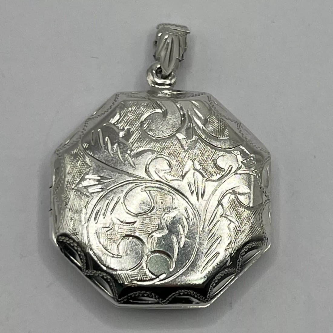 STERLING SILVER LOCKET: STERLING SILVER LOCKET This Sterling Silver Locket features an Octagon shape with a classic design, making it a timeless piece of fine jewelry. Crafted with 925 sterling silver, this pendant exudes el