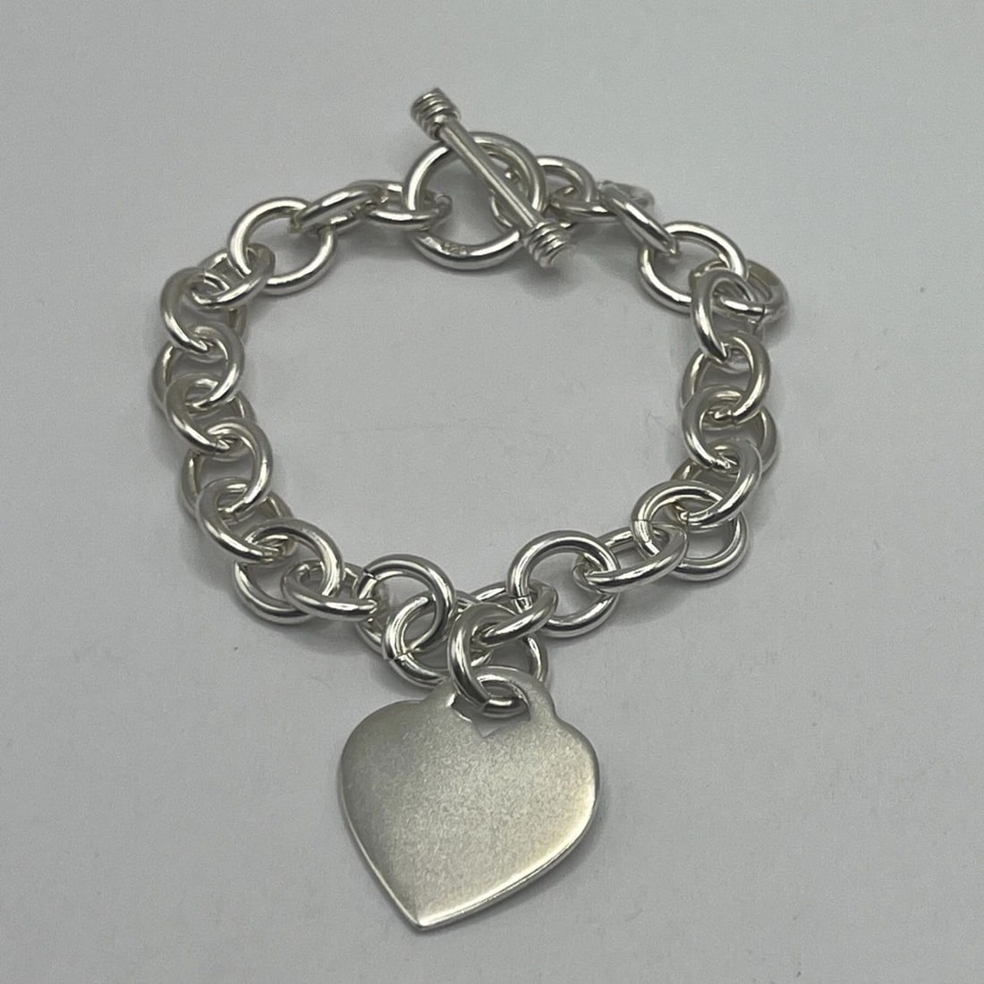 925 7" CIRCLE LINK CHARM BRACELET WITH HEART & TOGGLE LOCK 30.6 G: 925 7" CIRCLE LINK CHARM BRACELET WITH HEART & TOGGLE LOCK 30.6 G 925 7" CIRCLE LINK CHARM BRACELET WITH HEART & TOGGLE LOCK 30.6 G This is a 925 sterling silver charm bracelet measuring 7 inches in l