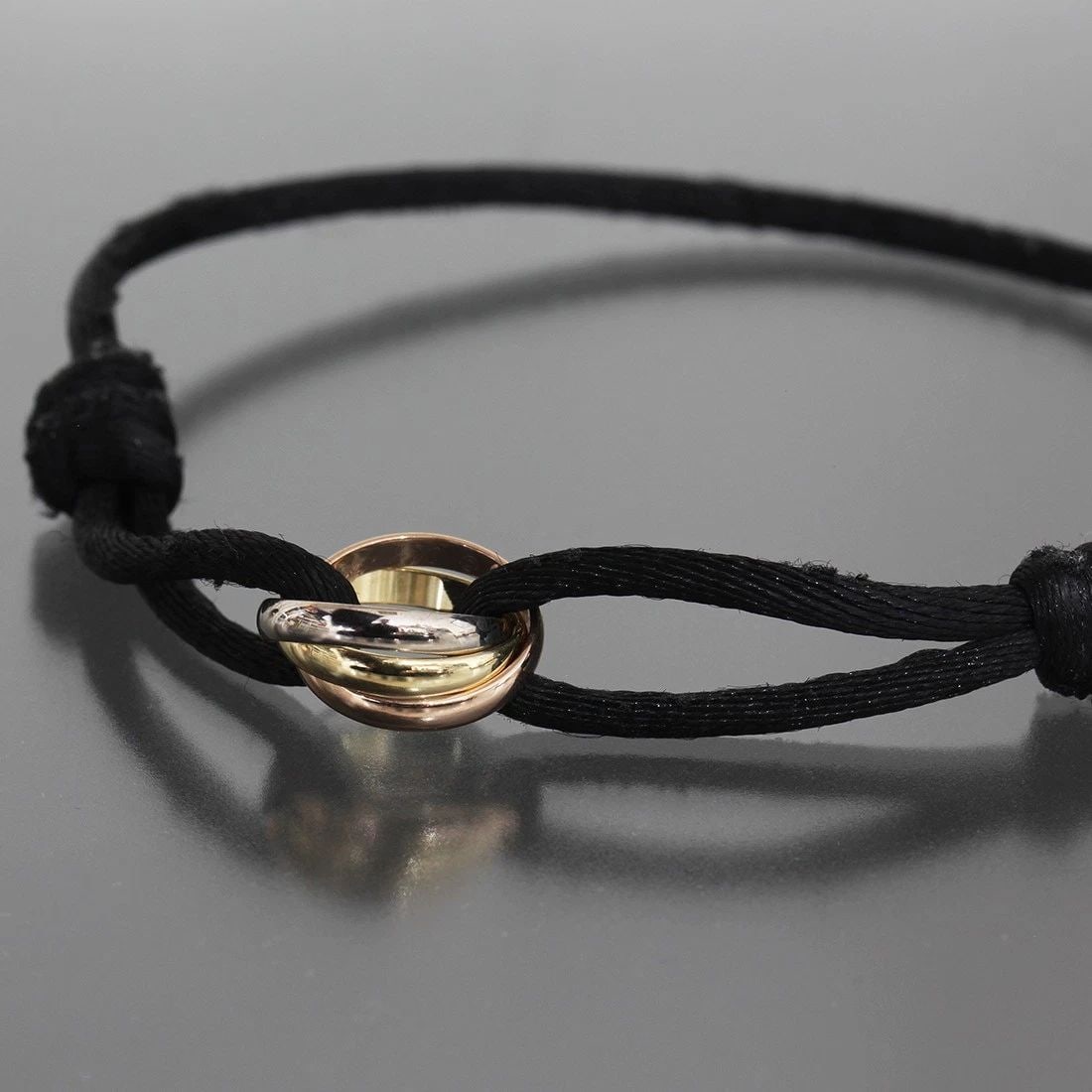 CARTIER TRINITY BRACELET COTTON CORD K18 NEWLY POLISHED ADJUSTABLE BANGLE 6398A: CARTIER TRINITY BRACELET COTTON CORD K18 NEWLY POLISHED ADJUSTABLE BANGLE 6398A Style : Bracelet Adjustable arm circumference: Approximately 13cm to 22cm Bracelet width: Approx. 1.9mm Top ring width: