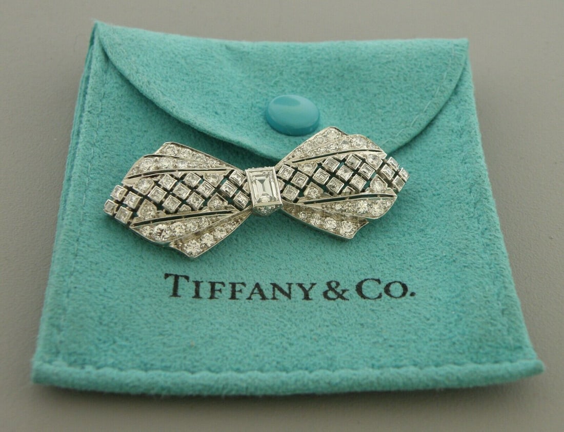 VINTAGE TIFFANY & CO PLATINUM BOW 3ct DIAMOND BROOCH: VINTAGE TIFFANY & CO. 3ct PLATINUM BROOCH PIN Brooch measures 1.85" H x 1.75" W Vintage Tiffany & Co. Platinum 3ct Diamond bow brooch with filigree design Center diamond apx 0.50ct Emerald cut Super c