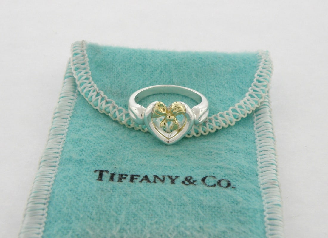 TIFFANY & Co. 18K GOLD STERLING SILVER LADIES BOW HEART: TIFFANY & CO. LADIES 18K STERLING SILVER RING SIZE 4 Ring size is a 4 (can easily be resized by your local jeweler) Ring measures 10.7mm wide in front 18K yellow gold & sterling silver pre-owned, ring