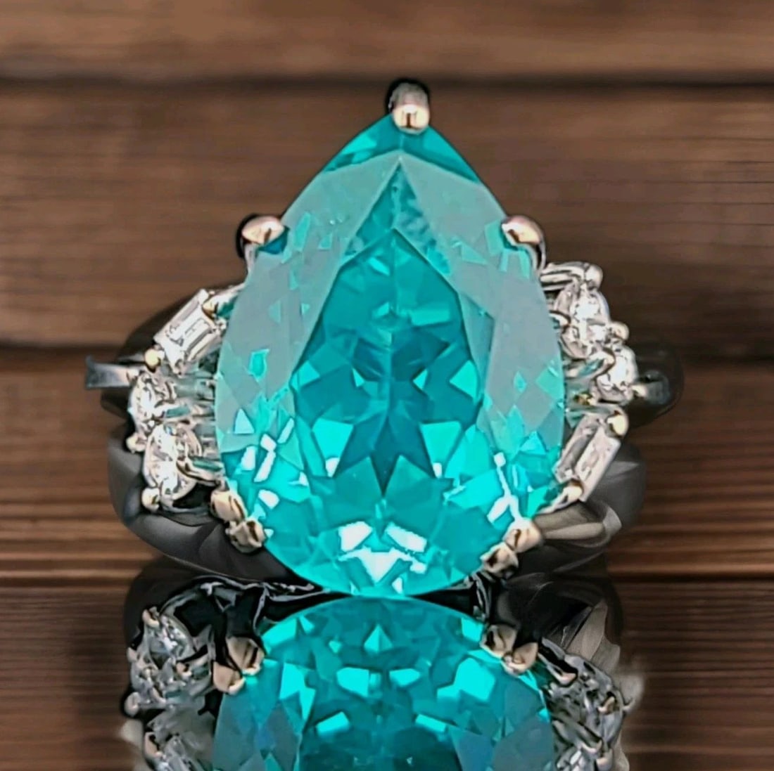 18K WHITE YELLOW GOLD ENGAGEMENT RING 7.89CT. LAB GROWN PARAIBA TOURMALINE PEAR: 18K WHITE YELLOW GOLD ENGAGEMENT RING 7.89CT. LAB GROWN PARAIBA TOURMALINE PEAR This 18K White Gold Engagement Ring features a beautiful lab grown Paraiba Tourmaline pear as the main stone, with a tot