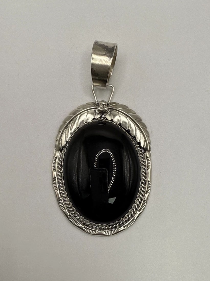 STERLING SILVER PENDANT WITH OVAL ONYX STONE: STERLING SILVER PENDANT WITH OVAL ONYX STONE This sterling silver pendant features a sleek oval onyx stone in a rich black color, making it a classic and elegant piece of fine jewelry. The 925 metal p