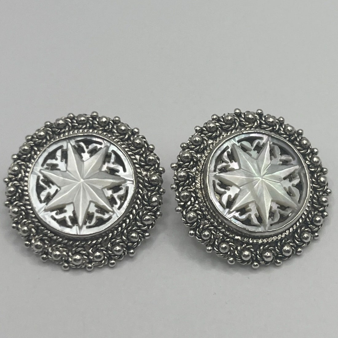 JERUSALEM SILVER CLIP EARRINGS WITH CARVED MOTHER OF PEARL FLOWER DESIGN: JERUSALEM SILVER CLIP EARRINGS WITH CARVED MOTHER OF PEARL FLOWER DESIGN These statement clip earrings are crafted in silver with a vintage Jerusalem design featuring a carved mother of pearl flower.