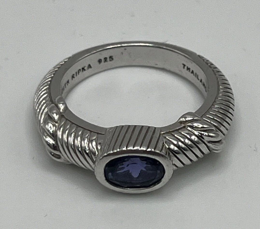JUDITH RIPKA STERLING SILVER, SYNTHETIC TANZANITE RING BAND SIZE 7: JUDITH RIPKA STERLING SILVER, SYNTHETIC TANZANITE RING BAND SIZE 7 This exquisite ring band is the perfect addition to any jewelry collection. Crafted by Judith Ripka, this piece features an oval-shap