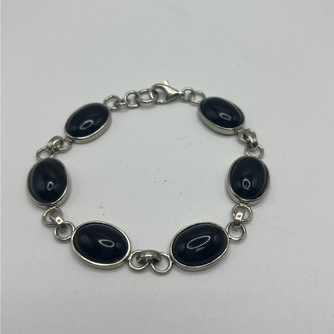 STERLING SILVER & BLACK ONYX 7" BRACELET: STERLING SILVER & BLACK ONYX 7" BRACELET This bracelet is made of 925 sterling silver with a chain style and features six black onyx gemstones. The main stone is black onyx, giving the piece a sleek a