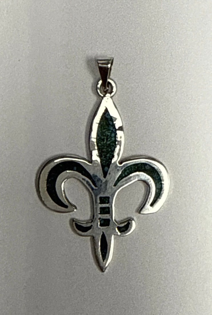 FLEUR DE LIS STERLING SILVER & TURQUOISE CHIP INLAY PENDANT: FLEUR DE LIS STERLING SILVER & TURQUOISE CHIP INLAY PENDANT The Fleur De Lis Sterling Silver & Turquoise Chip Inlay Pendant is a beautifully crafted piece of jewelry that combines the elegance of