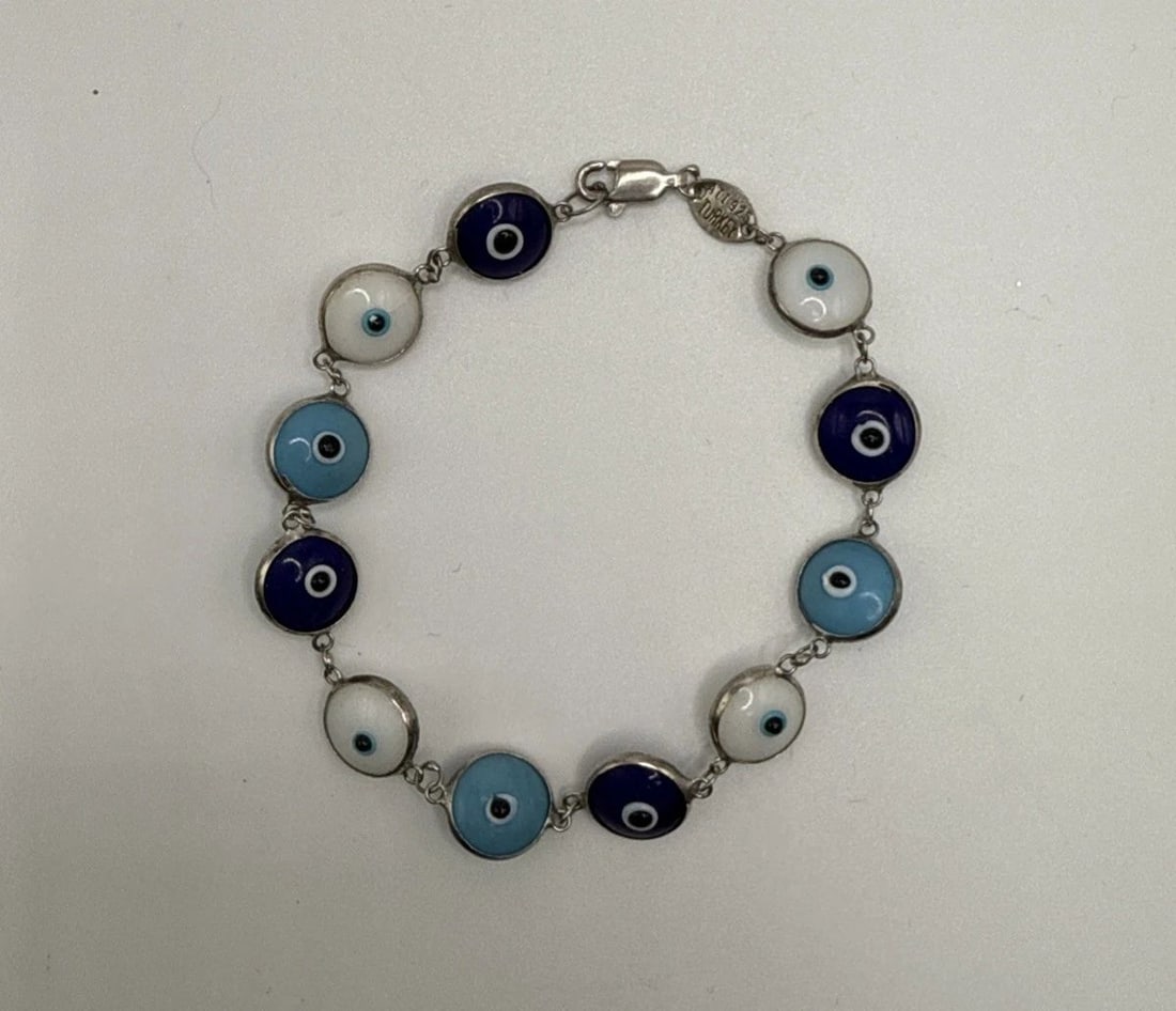 7" EVIL EYE BRACELET: 7" EVIL EYE BRACELET The 7" Evil Eye Bracelet is a stylish and charming piece of fashion jewelry. With a blue color and silver metal, this bracelet exudes a trendy and unique allure. The evil eye desi