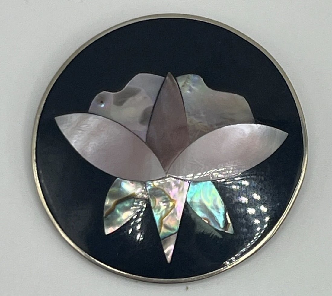 ALPACA STERLING SILVER MEXICAN BROOCH WITH MOTHER OF PEARL FLOWER: ALPACA STERLING SILVER MEXICAN BROOCH WITH MOTHER OF PEARL FLOWER This Alpaca Sterling Silver Mexican brooch features a flower design made of Mother of Pearl in multicolor hues. The brooch is crafted