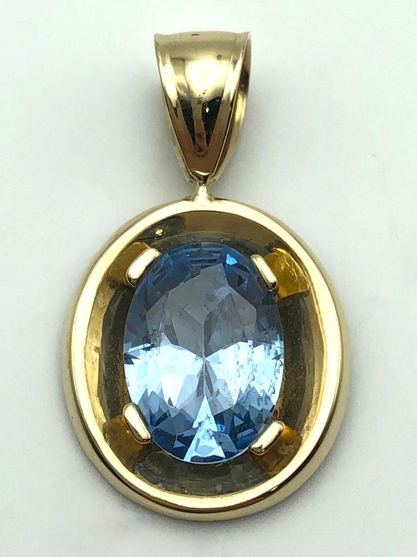 14K GOLD OVAL SHAPED PENDANT SET WITH A 8CT BLUE TOPAZ: 14K GOLD OVAL SHAPED PENDANT SET WITH A 8CT BLUE TOPAZ 14k Gold oval shaped Pendant set with a 8ct Blue Topaz Condition: Used Material: 14k Yellow Gold Pendant Weight: 5.7 grams Pendant Size: 32mm x 1