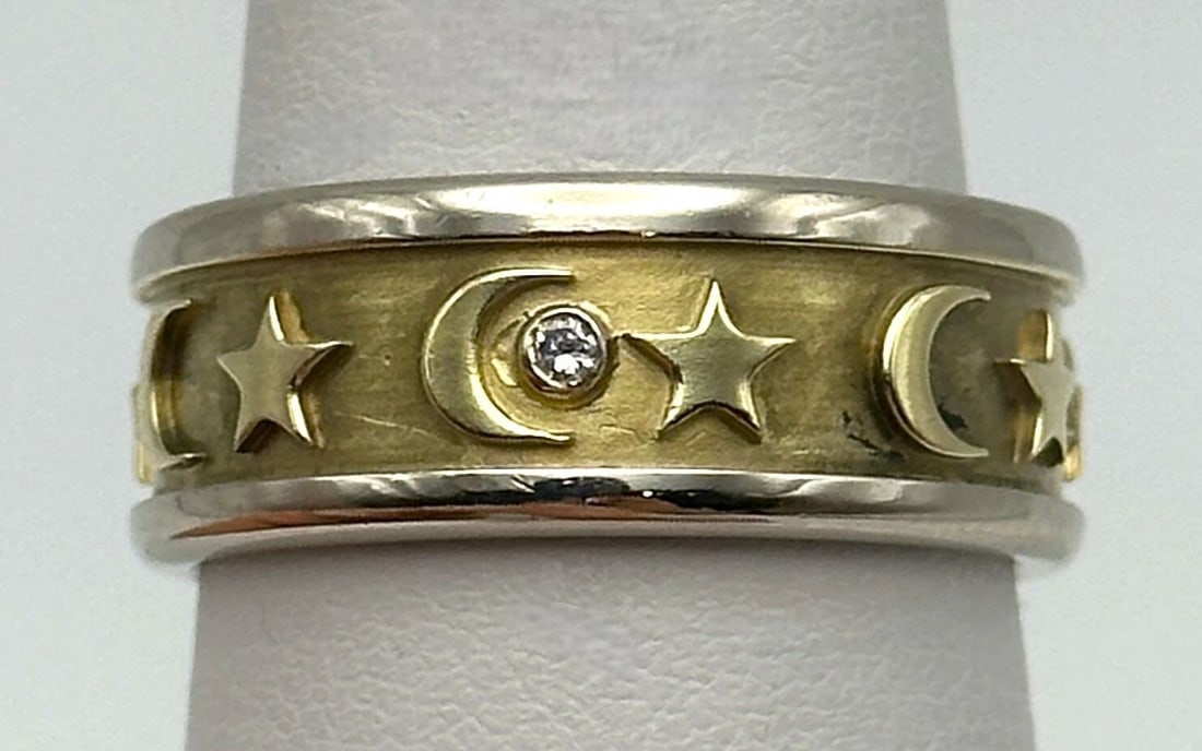 14K TWO TONE GOLD BAND WITH STARS CRESCENT MOON AND 0.06CTS DIAMONDS 9.9 GRAMS: 14k Two Toned Gold Band with Stars Crescent Moon and 0.06cts of Diamonds Condition: Used Material: 14k Two Toned White/Yellow Gold Ring Size: 8 Weight: 9.9 grams Width: 7.9mm Stone Info: Three round b