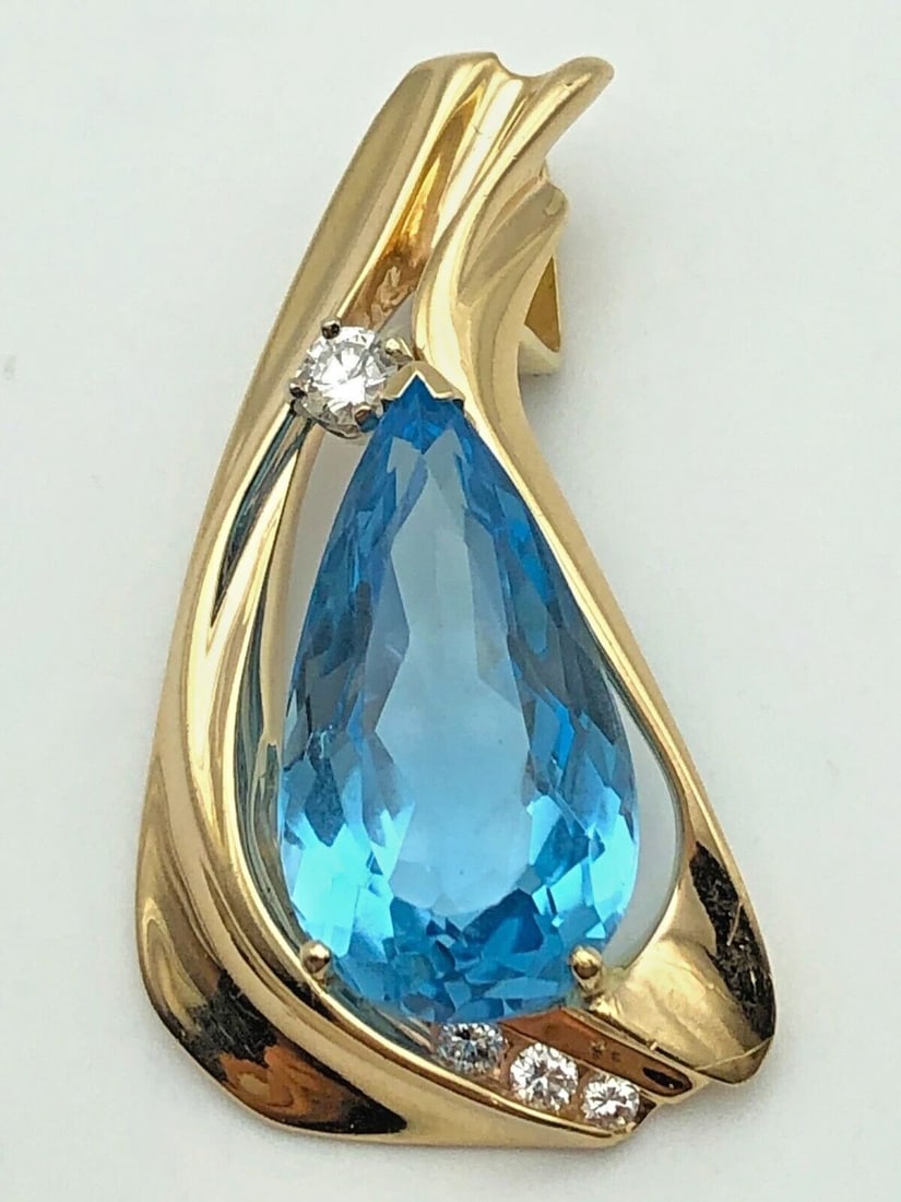 14K GOLD PENDANT WITH SWISS BLUE TOPAZ AND 0.18CTS OF DIAMONDS 8.5 GRAMS: 14k Gold Pendant with Swiss Blue Topaz and 0.18cts of Diamonds Condition: Used Material: 14k Yellow Gold Pendant Size: 37mm x 20mm Total Weight: 8.5 grams Stone Info: 21mm x 11.6mm x 8.1mm Swiss Blue