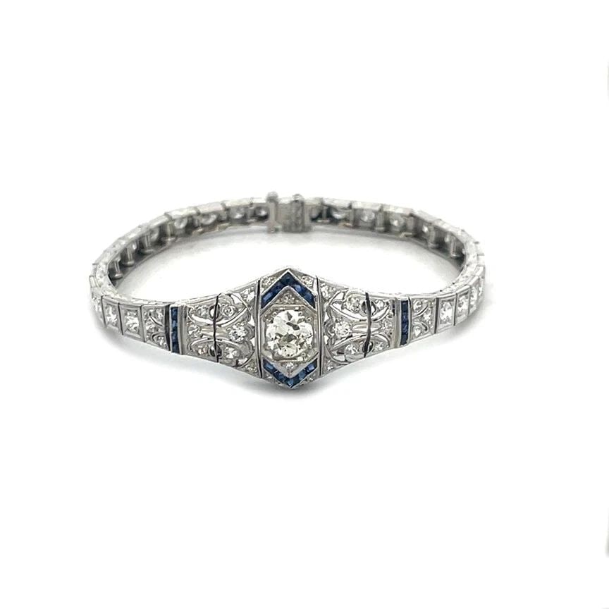 PLATINUM ART DECO BRACELET 3.5CT DIAMOND FLORAL CENTERPIECE CUBE LINKS: The platinum Art Deco bracelet is a stunning piece of antique jewelry featuring a floral centerpiece with a sparkling diamonds accented with blue colored stones, the milgrain filigree asymmetrical sha