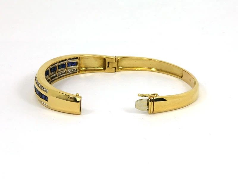 DIAMOND SAPPHIRE GOLD BRACELET 18K YELLOW BANGLE: DIAMOND SAPPHIRE GOLD BRACELET 18K YELLOW BANGLE The Diamond Sapphire Gold Bracelet is a stunning piece of fine jewelry made of natural white diamond and intense blue sapphire gemstones. The oval-shap