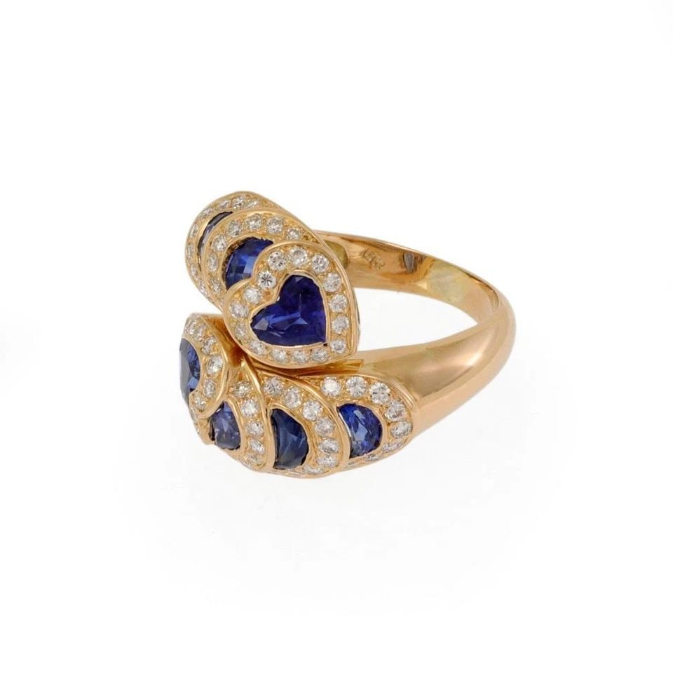 RING DIAMOND& BLUE GEMSTONE 18K YELLOW GOLD HEARTS BYPASS SIZE 9.5 ESTATE: RING DIAMOND& BLUE GEMSTONE 18K YELLOW GOLD HEARTS BYPASS SIZE 9.5 ESTATE This luxury ring features beautiful diamonds and blue gemstones set in 18k yellow gold with a bypass style design. The heart- 