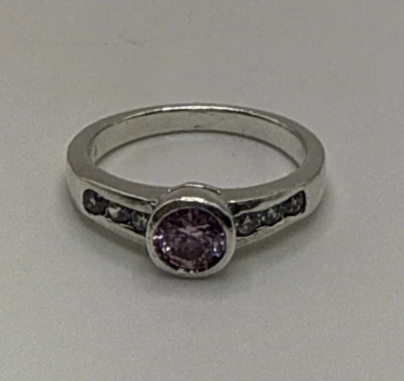 STERLING SILVER RING WITH PINK CENTER STONE AND COLORLESS SIDE STONES SIZE 5.75: STERLING SILVER RING WITH PINK CENTER STONE AND COLORLESS SIDE STONES SIZE 5.75 This sterling silver ring features a beautiful pink center stone surrounded by colorless side stones, giving it a stunni