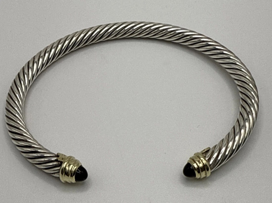 DAVID YURMAN 5MM STERLING SILVER BLACK ONYX & 18K GOLD CABLE CUFF BRACELET: DAVID YURMAN 5MM STERLING SILVER BLACK ONYX & 18K GOLD CABLE CUFF BRACELET The David Yurman 5mm Sterling Silver Black Onyx & 18K Gold Cable Cuff Bracelet is a luxurious and stylish piece of fine jewel
