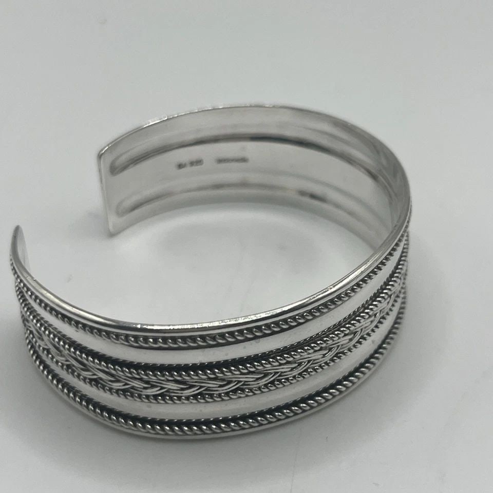 STERLING SILVER CUFF WITH ROPING AND BRAIDING DETAILS: STERLING SILVER CUFF WITH ROPING AND BRAIDING DETAILS STERLING SILVER CUFF WITH ROPING AND BRAIDING DETAILS This sterling silver cuff bracelet features intricate roping and braiding details, adding a 