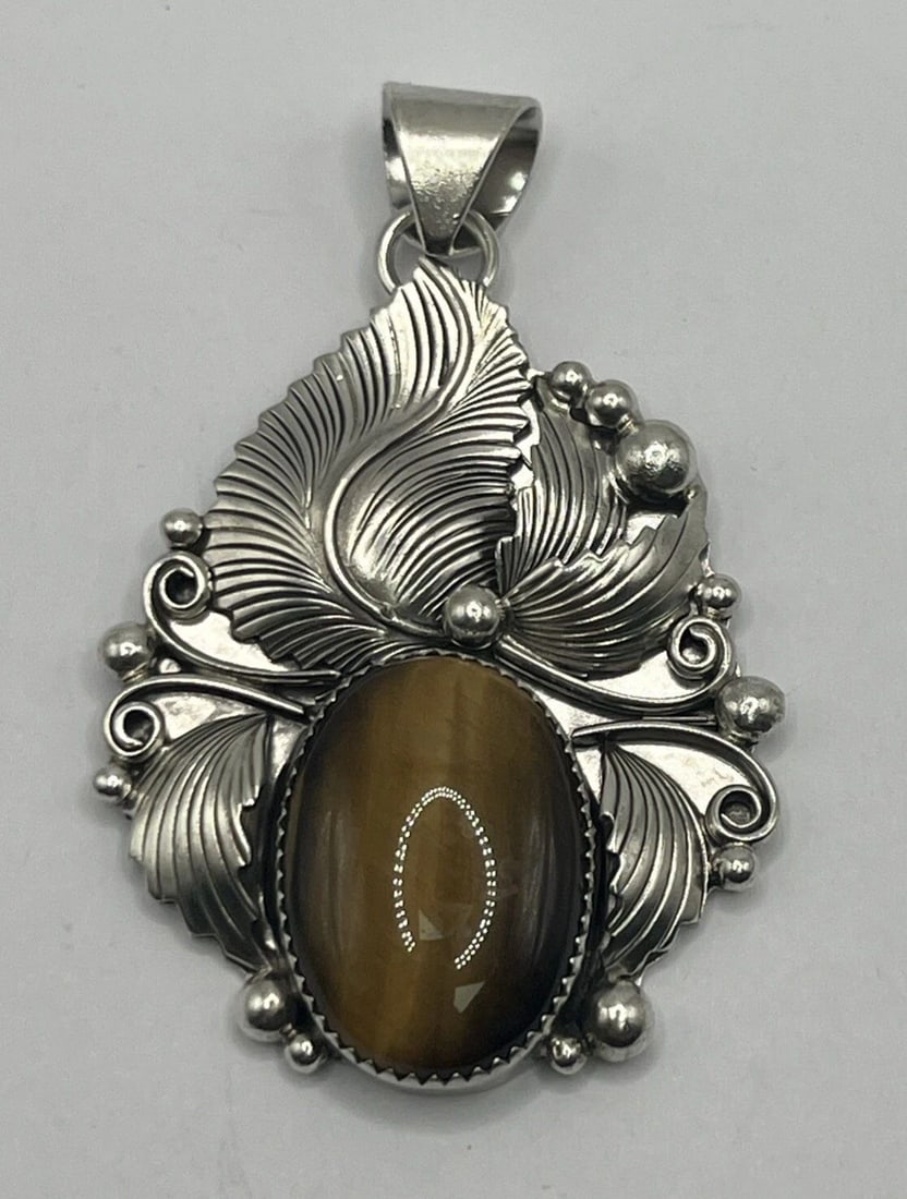 STERLING SILVER & TIGERS EYE LEAF PENDANT 23.2 GRAMS: STERLING SILVER & TIGERS EYE LEAF PENDANT 23.2 GRAMS STERLING SILVER & TIGERS EYE LEAF PENDANT 23.2 GRAMS This Sterling Silver pendant features a Teardrop leaf design adorned with an Oval-shaped Tiger