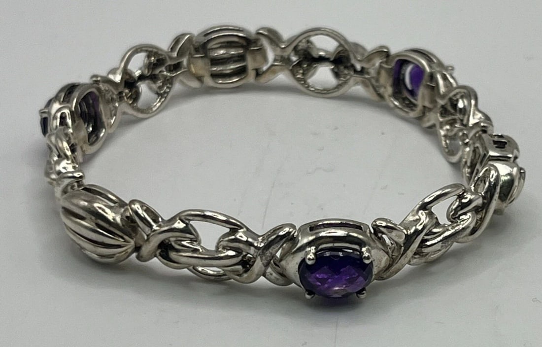 STERLING SILVER BRACELET WITH PURPLE STONES 7.5": STERLING SILVER BRACELET WITH PURPLE STONES 7.5" STERLING SILVER BRACELET WITH PURPLE STONES 7.5" This Sterling Silver Bracelet features three oval-shaped purple stones set in a tennis style design. T
