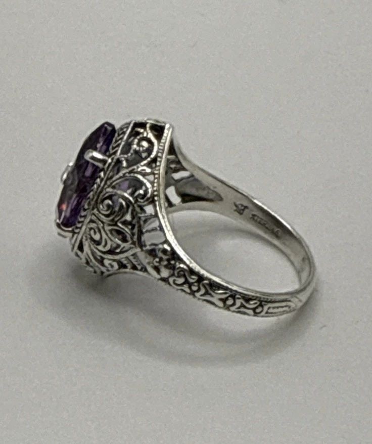 VICTORIAN STYLE STERLING SILVER PURPLE STONE FILIGREE RING W COLORLESS STONE S7: VICTORIAN STYLE STERLING SILVER PURPLE STONE FILIGREE RING W COLORLESS STONE S7 The product is a Victorian style sterling silver ring with a purple stone and filigree design. The ring is size 7 and fe
