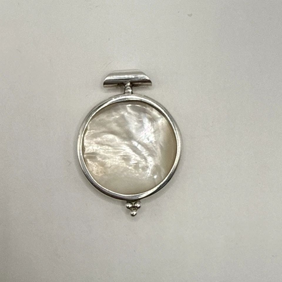 STERLING SILVER ROUND MOTHER OF PEARL PENDANT: STERLING SILVER ROUND MOTHER OF PEARL PENDANT This Sterling Silver Round Mother of Pearl Pendant features a classic and elegant design, perfect for everyday wear. The white mother of pearl main stone 